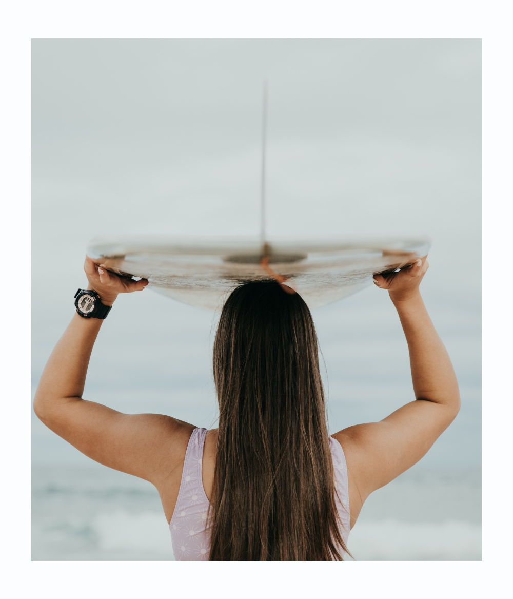 A black and pink Maxum brand analog-digital watch with a resin strap and buckle closure, featuring a digital display and multiple watch features. worn on wrist of woman holding surfboard over her head