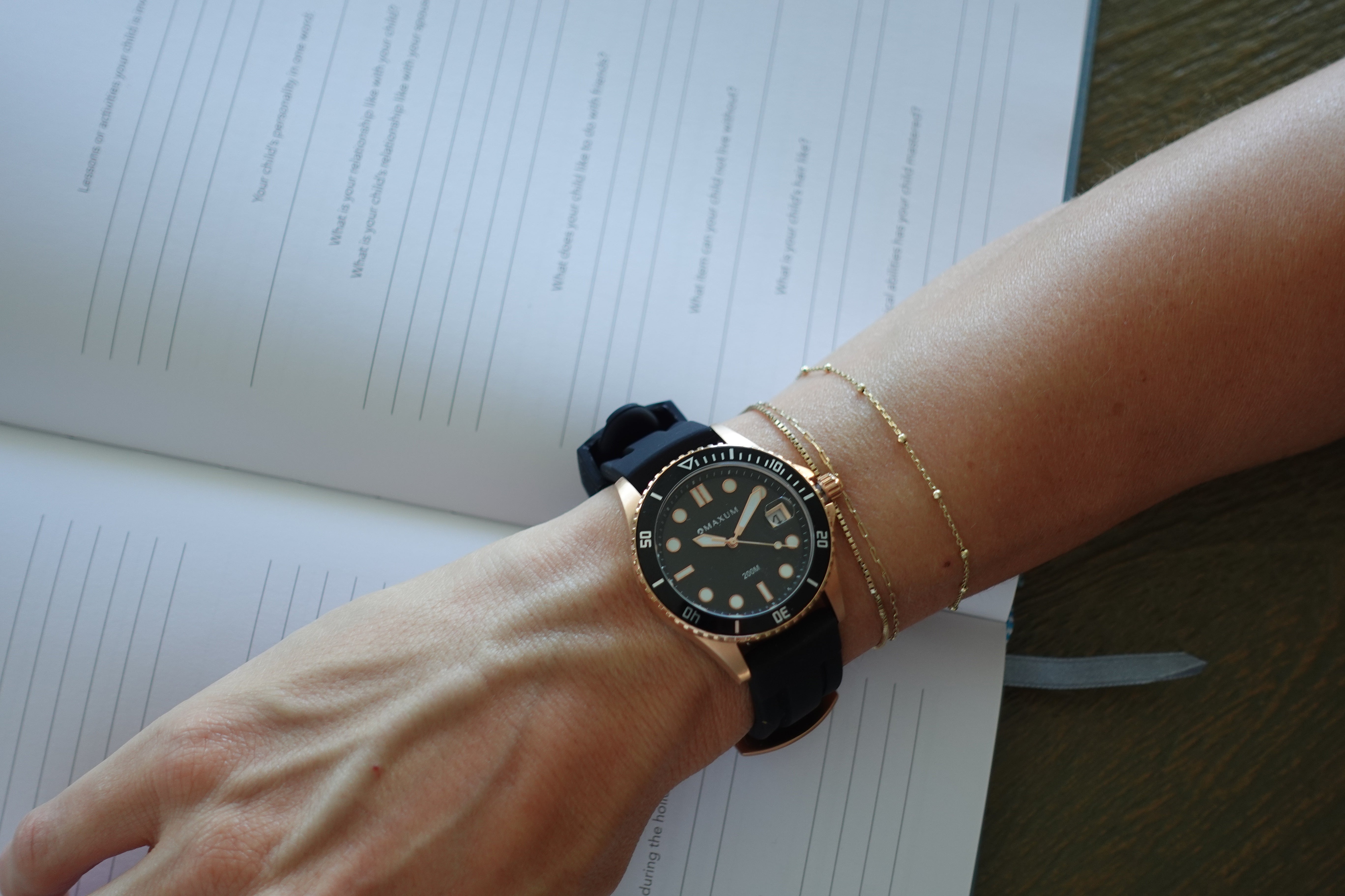 Maxum Liberty black analogue date watch with a rose-gold case on a hand on a surface with text
