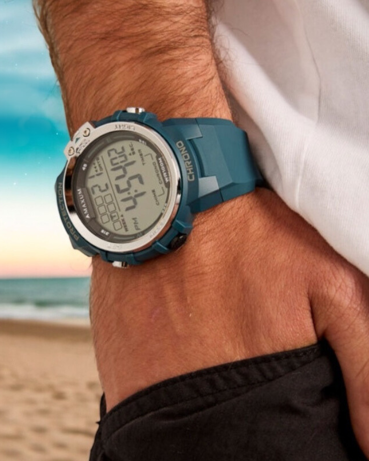 Maxum Explorer Blue Digital Watch with a  blue resin strap, featuring a digital display with silver accent on wrist shot with beach background